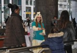 Dressed for Mardi Gras, young drug prevention volunteer hands out drug education booklets to a child at a train station in the heart of Brussels, Belgium.