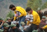Pakistan Volunteer Assist team members hand out food packs to children in the devastated area.